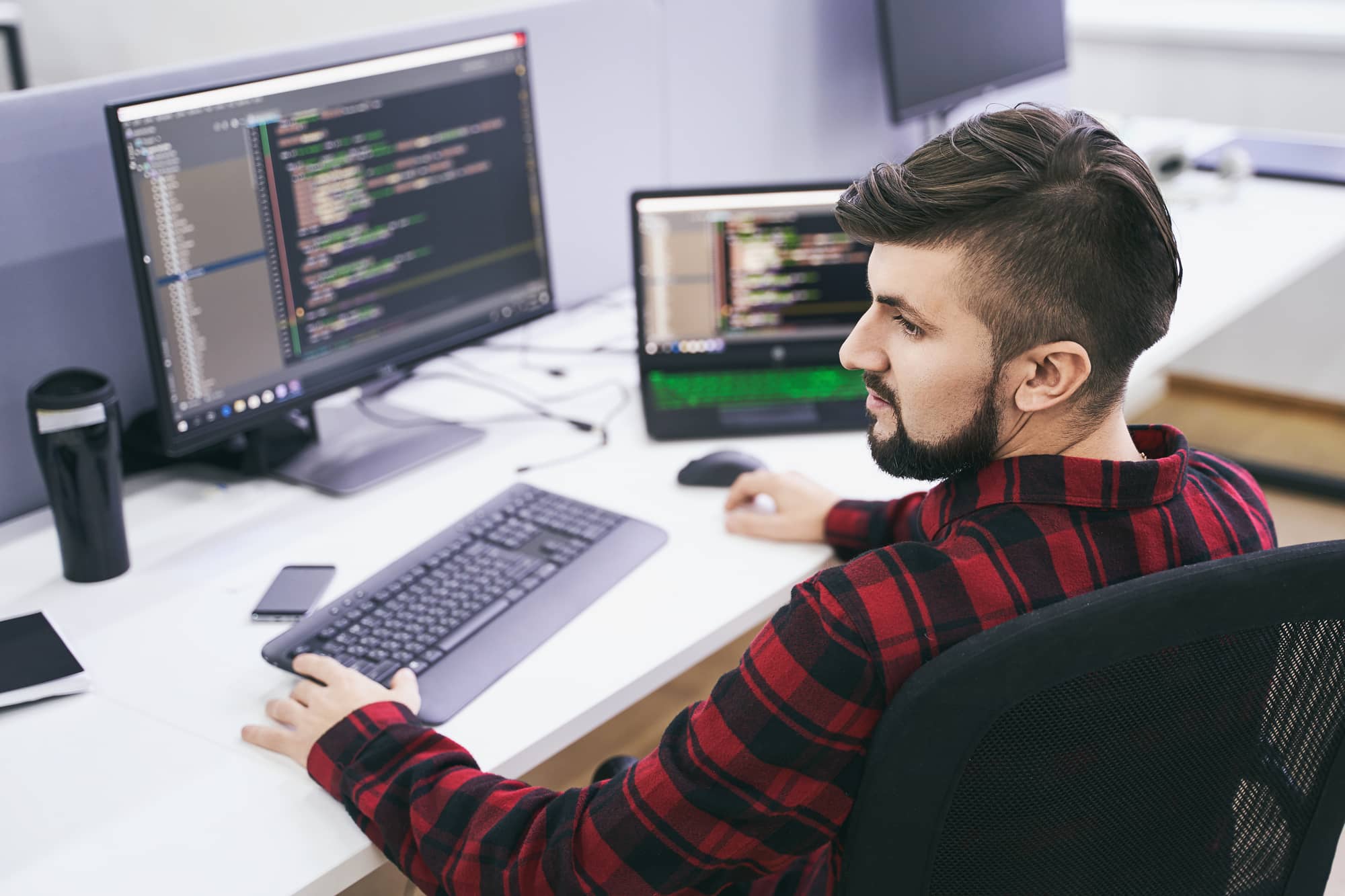 A man sitting at a desk and working on computer code